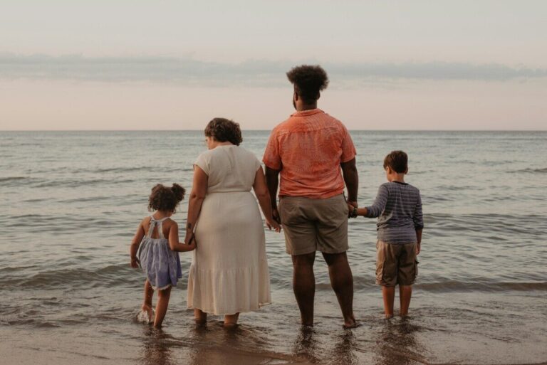 Family of four standing together at the shoreline