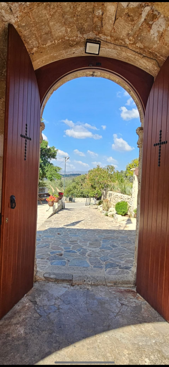 Open wooden doors framing a sunny stone path