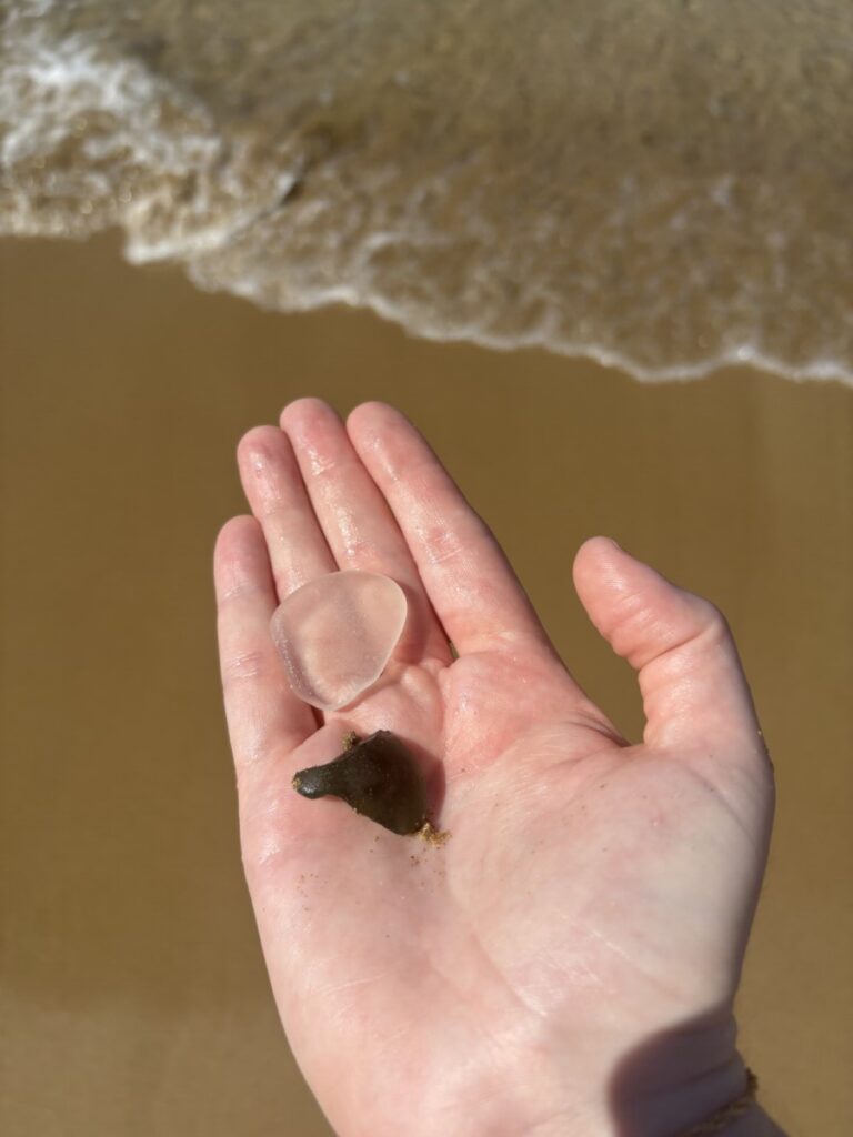 Open hand holding sea glass at the water's edge