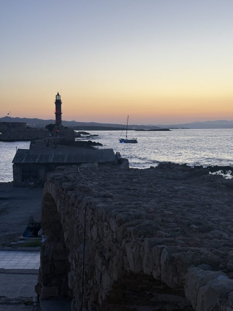 Lighthouse on a stone harbor wall at sunset