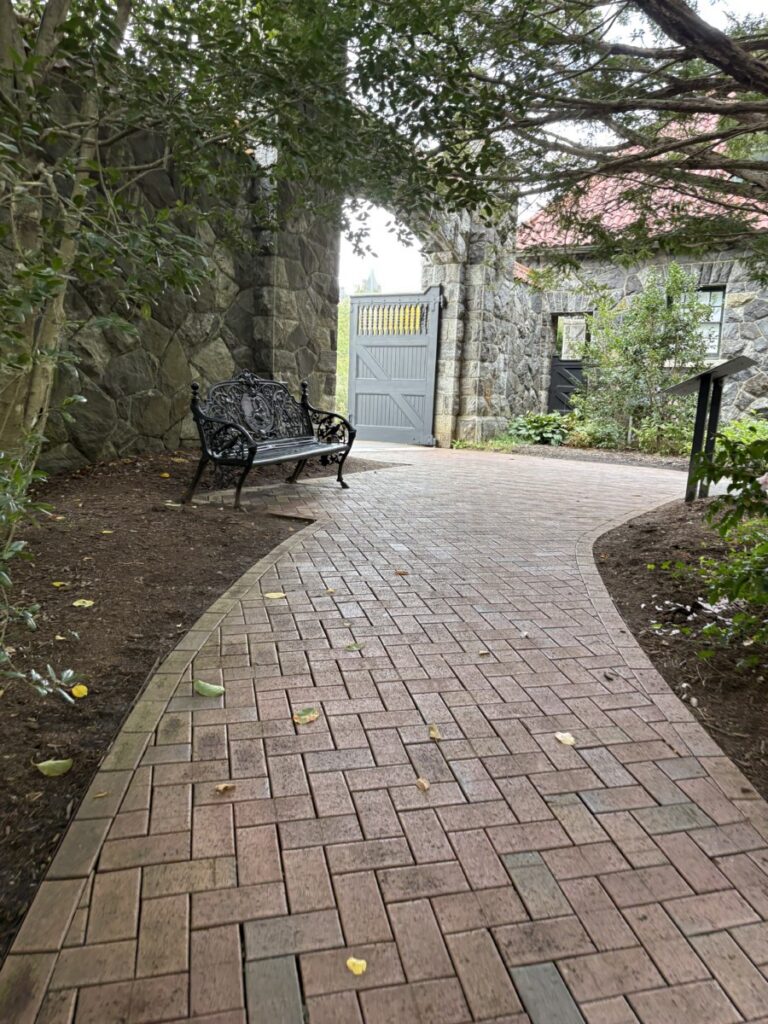 Brick garden path with a bench under shady trees