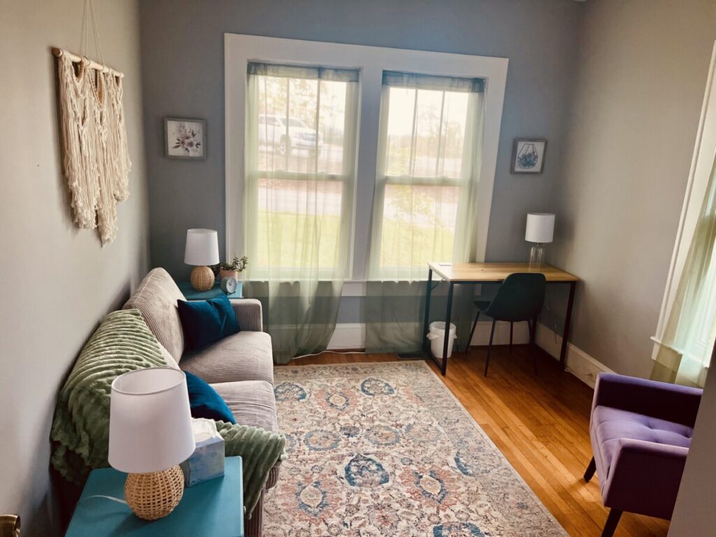 Therapy room at the Hendersonville office with a sofa, purple armchair and sunny windows