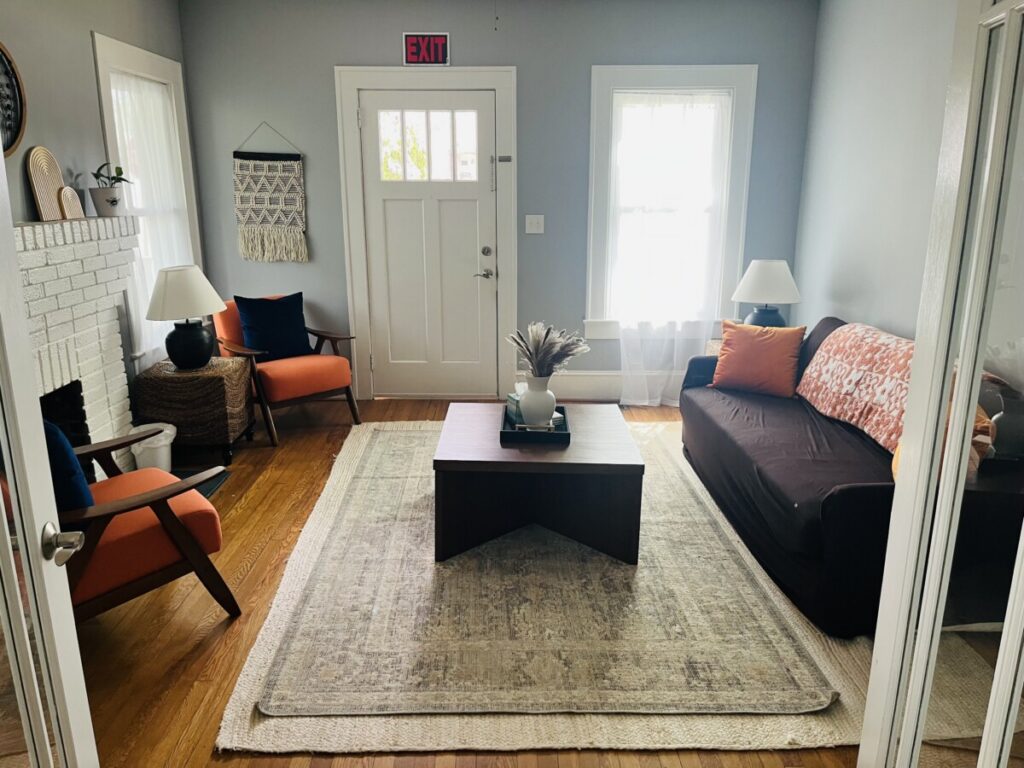 Therapy room at the Hendersonville office with orange armchairs, a sofa and a white brick fireplace