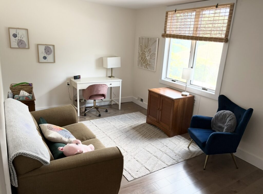 Therapy room at the Asheville office with a sofa, blue armchair and natural light